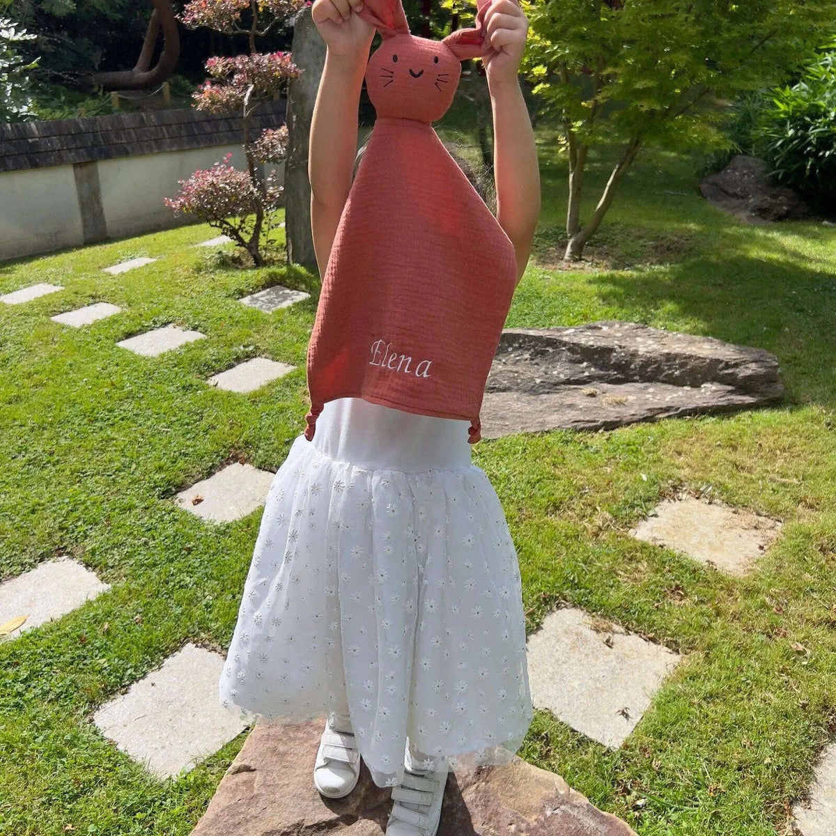 Enfant tenant un doudou personnalisé terracotta brodé au prénom Elena